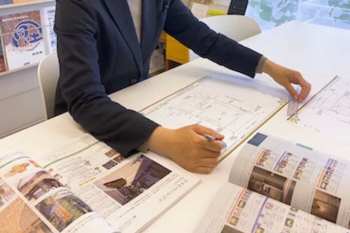 設計図とカタログを机に広げるプランナー