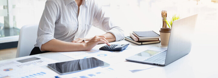 パソコンを見ながら電卓で計算する女性